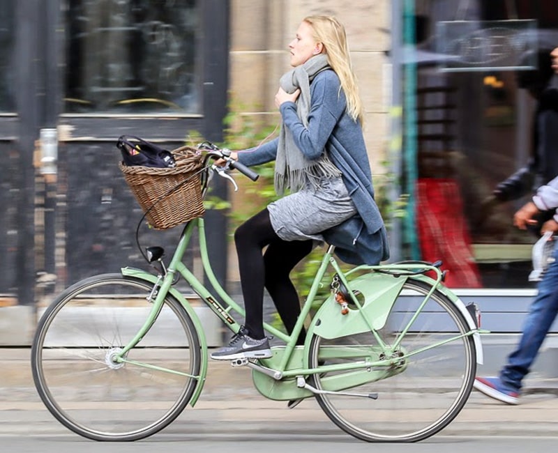 Девушка в плаще на велосипеде с кожухом на цепи