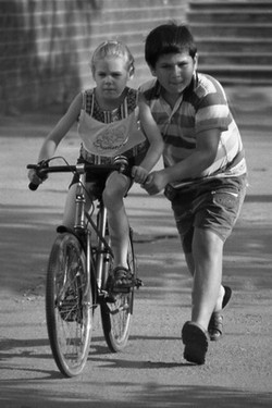 Брат вчить сестру кататися на велосипеді 